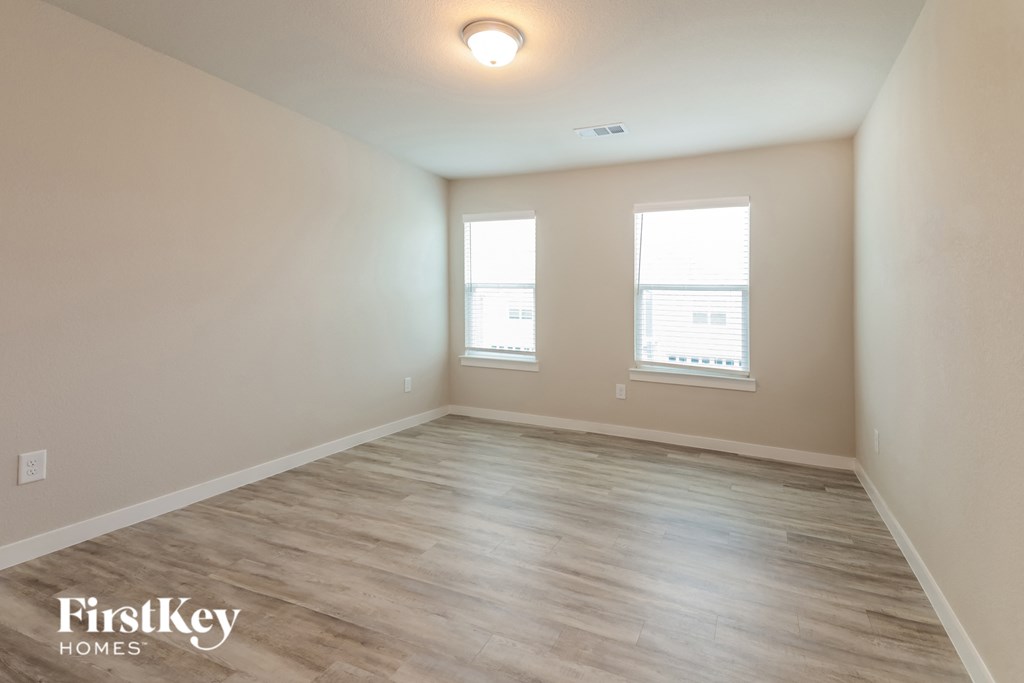 the spacious living room with wood flooring and two windows