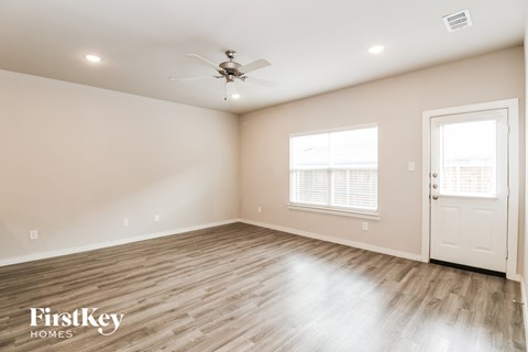 the spacious living room with wood flooring and a ceiling fan