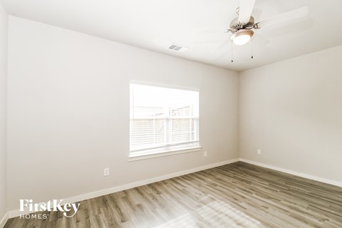 a bedroom with white walls and wood floors and a ceiling fan