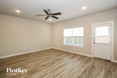 the spacious living room with hardwood flooring and a ceiling fan
