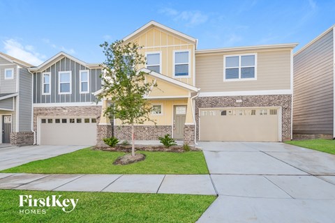 a beige house with two garage doors and a lawn