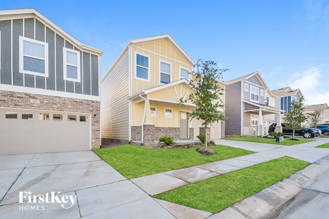a street view of three homes with a sidewalk and grass