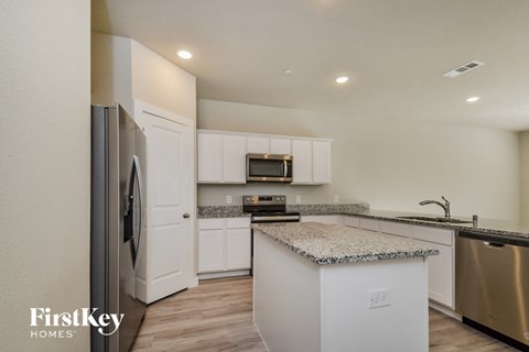 a kitchen with white cabinets and granite counter tops and stainless steel appliances