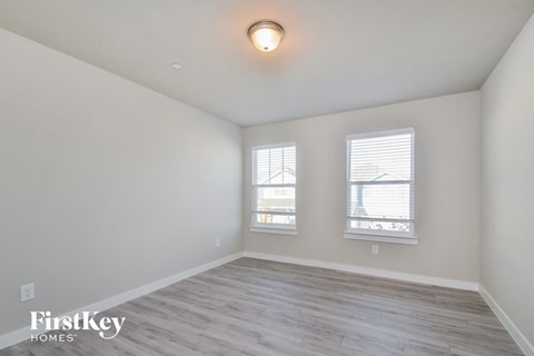 the living room of an apartment with wood flooring and two windows