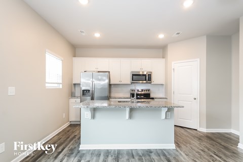 A kitchen with a refrigerator, microwave, and sink.