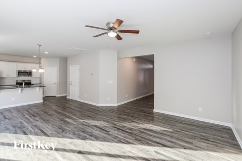 A spacious room with a ceiling fan and a wooden floor.