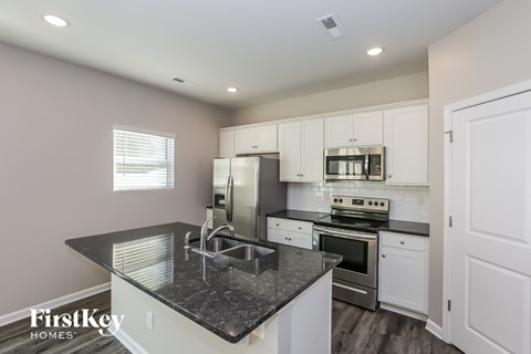 A kitchen with a black countertop and white cabinets.