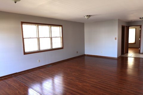 an empty living room with wood floors and a window