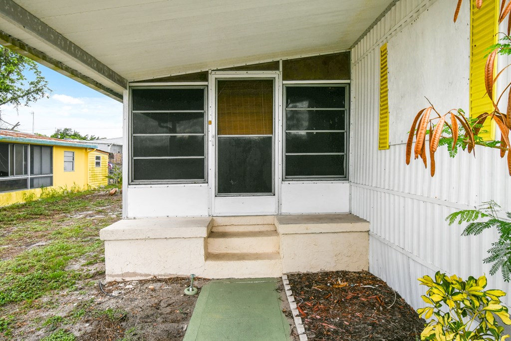 A white house with a green mat in front of it.
