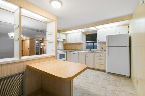 A kitchen with a wooden table and white appliances.
