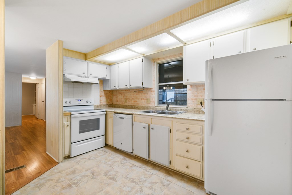 A kitchen with white appliances and wooden cabinets.