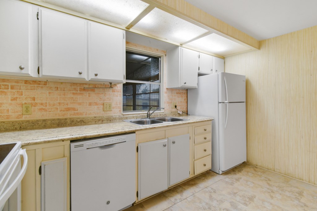 A kitchen with white cabinets and a refrigerator.