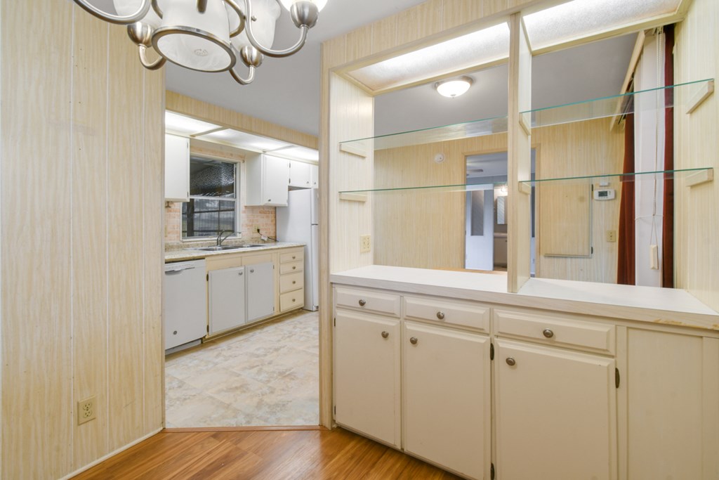 A kitchen with white cabinets and a wooden floor.