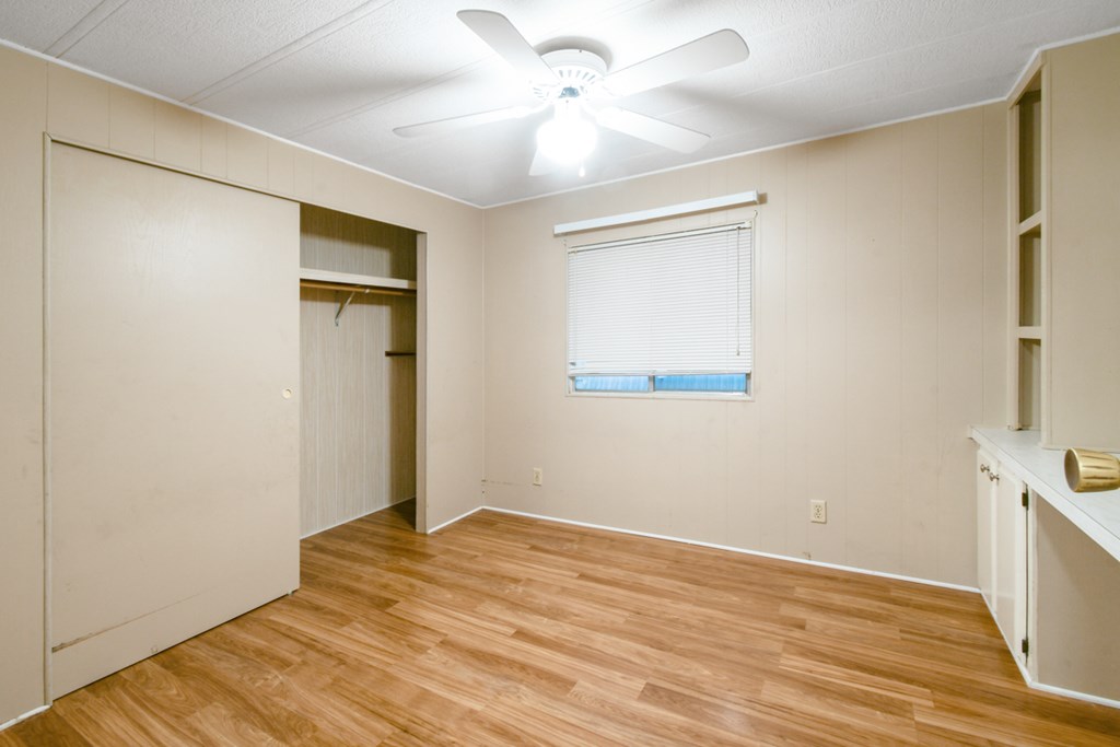 A room with a ceiling fan and a window with blinds.
