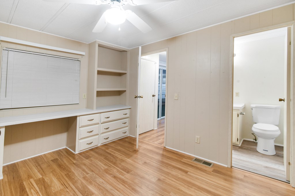 A room with a desk, drawers, and a toilet in the background.