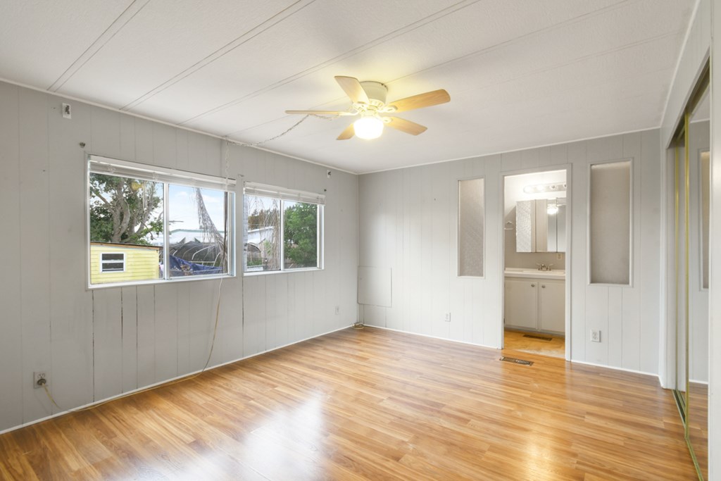 A room with a ceiling fan and wooden floors.