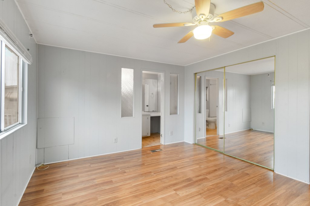 A room with a ceiling fan and mirrored door.