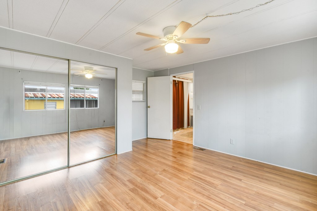 A room with a ceiling fan and wooden flooring.
