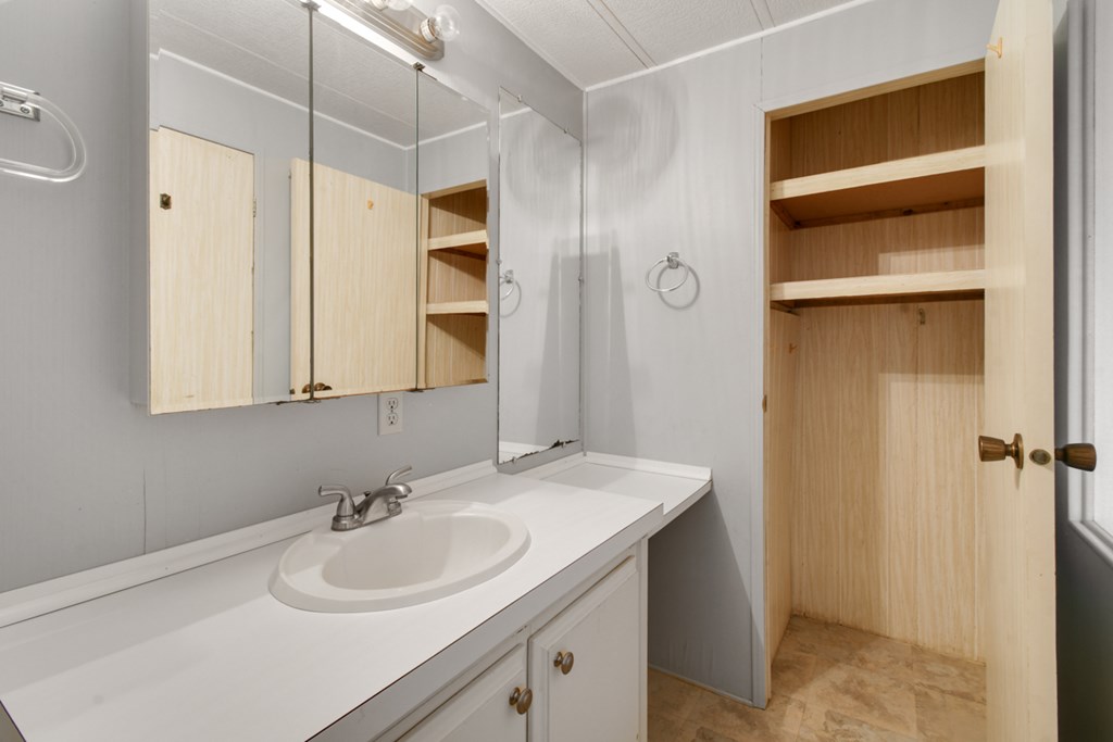A bathroom with a sink, mirror, and wooden shelves.