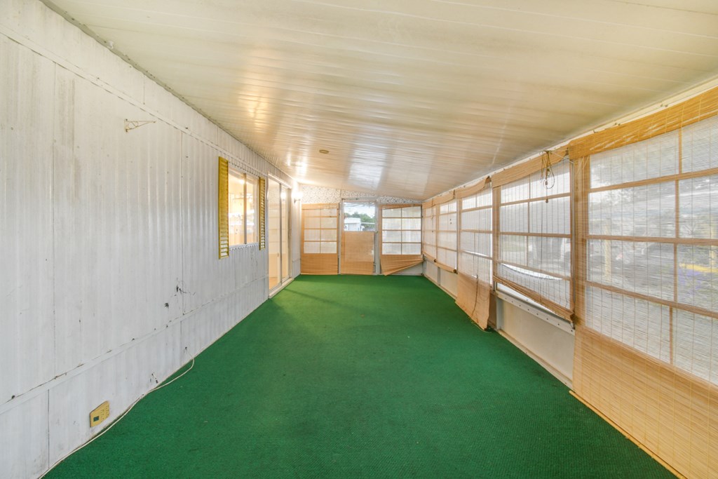 A long hallway with green carpeting and white walls.
