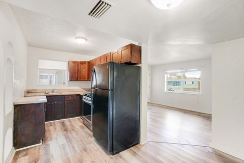 A black refrigerator in a kitchen with wooden cabinets.