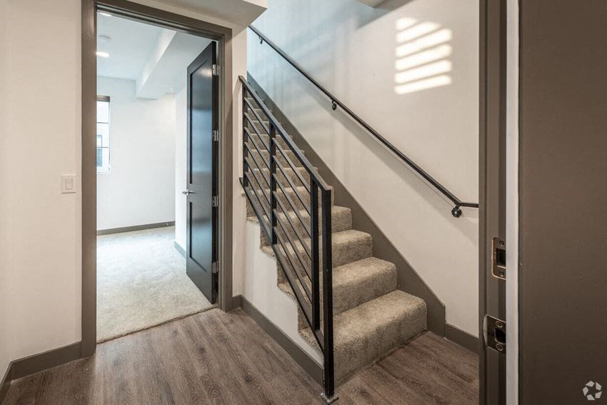 a stairway with a glass railing and a white wall and a door