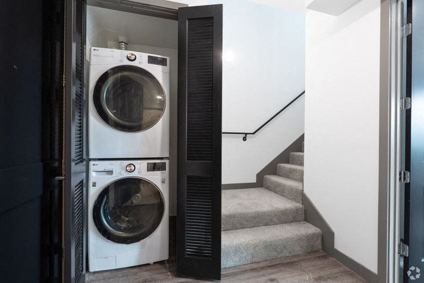 a washing machine and a dryer in a small room next to stairs