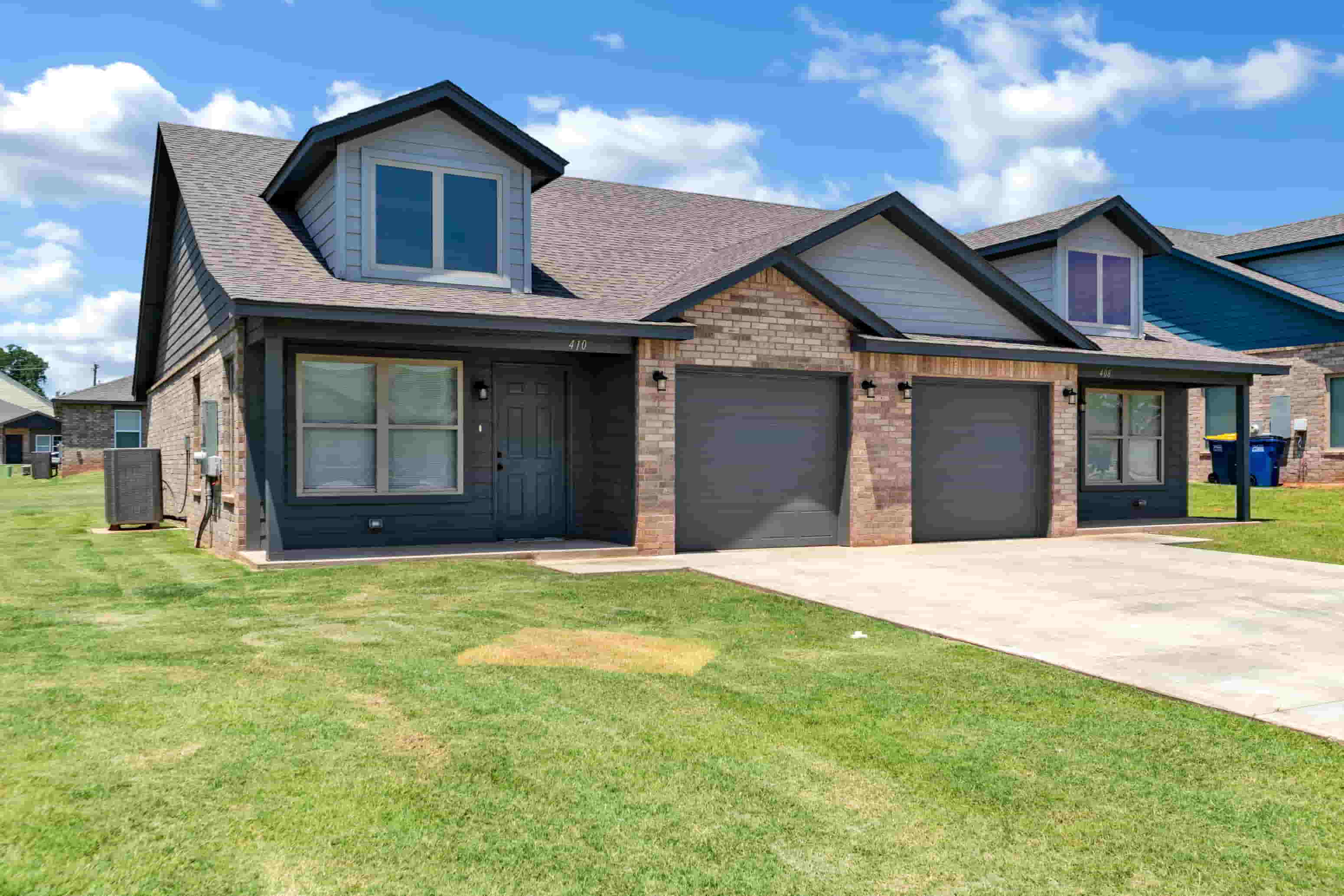 a house with two garage doors and a sidewalk in front of it