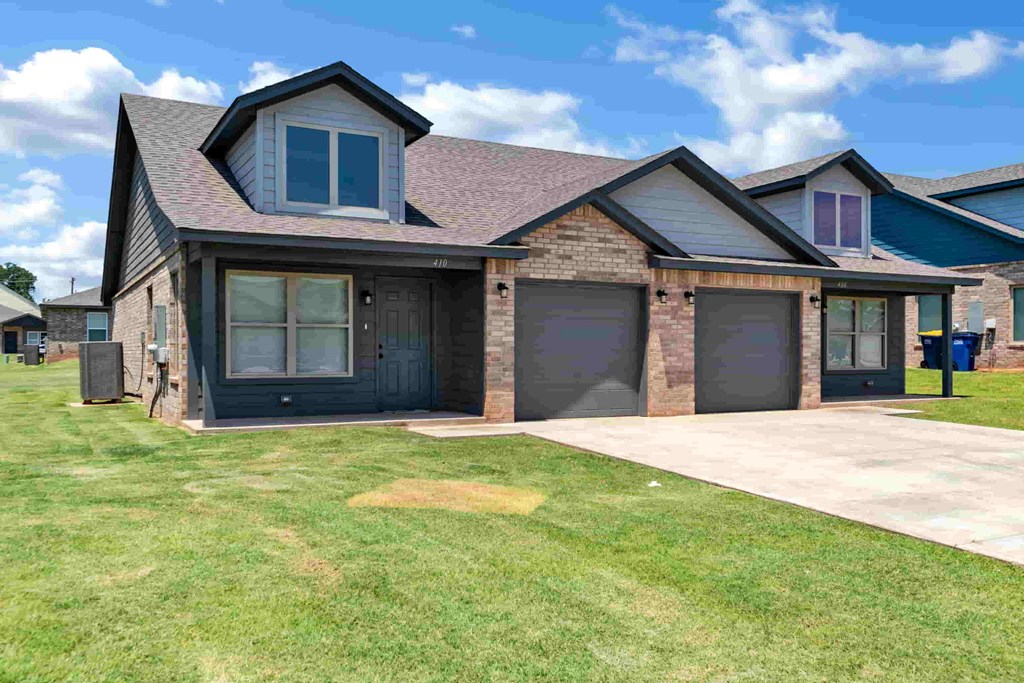 a house with two garage doors and a sidewalk in front of it