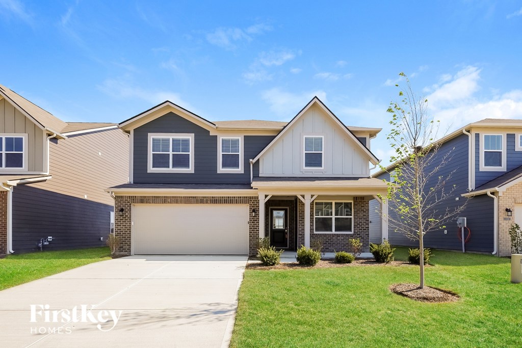 A house with a garage and a tree in front.