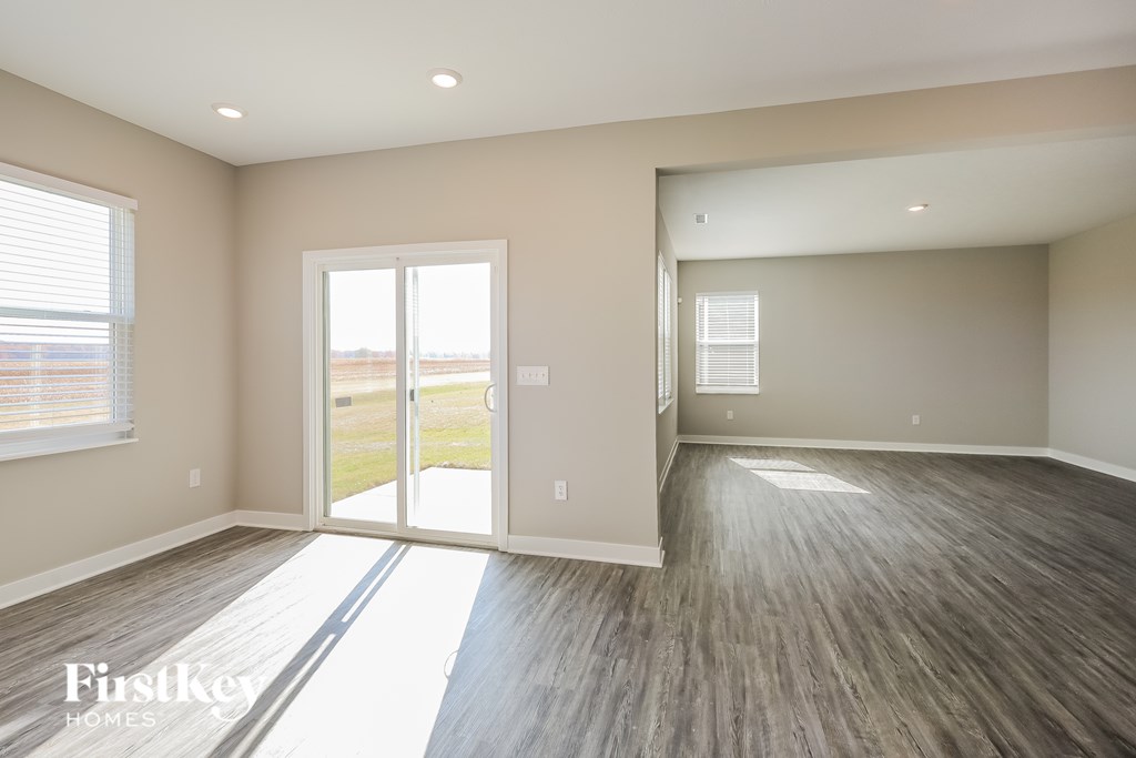 A spacious room with wooden flooring and a large window.