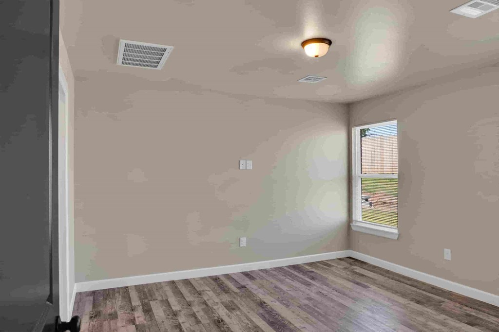 an empty living room with a window and wooden floors