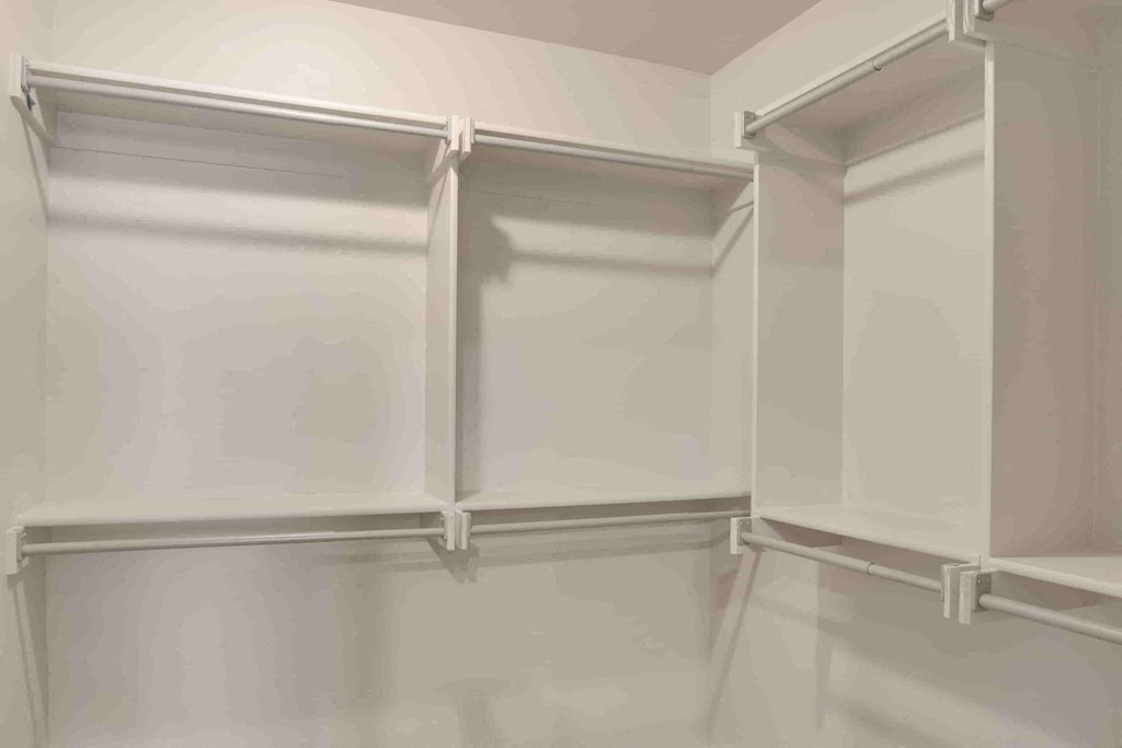 a walk in closet with white walls and white closet doors