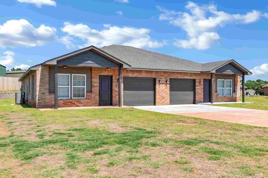 a brick house with two garage doors and a lawn
