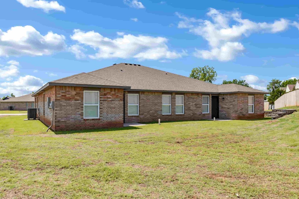 a brick house with a grassy yard and a blue sky
