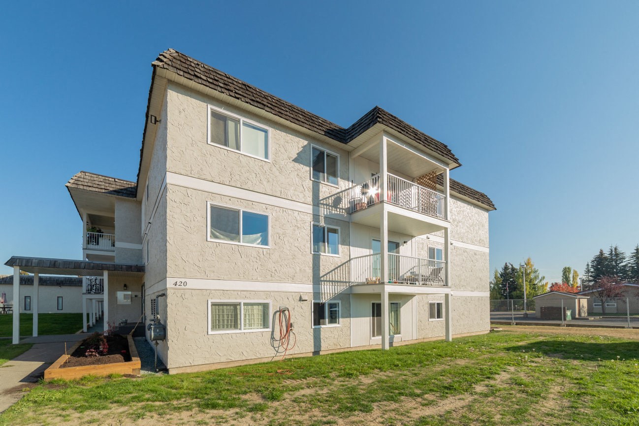 a view of a white apartment building with a grass yard