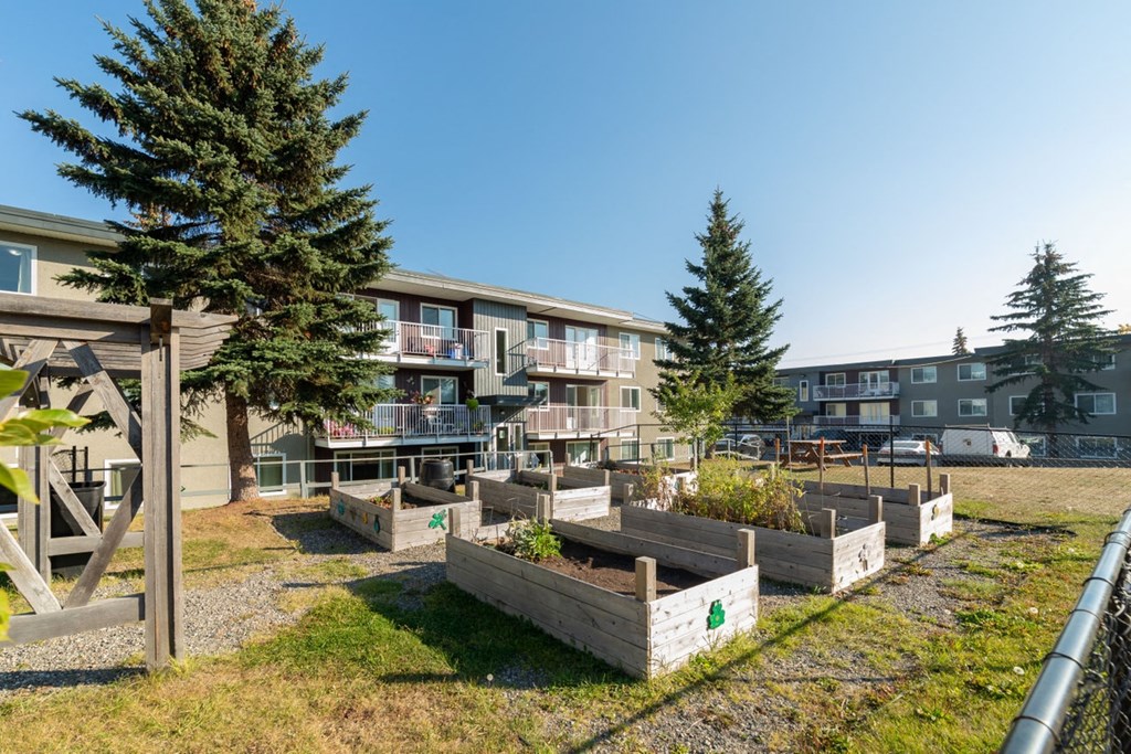 a community garden with wooden planters in front of an apartment building