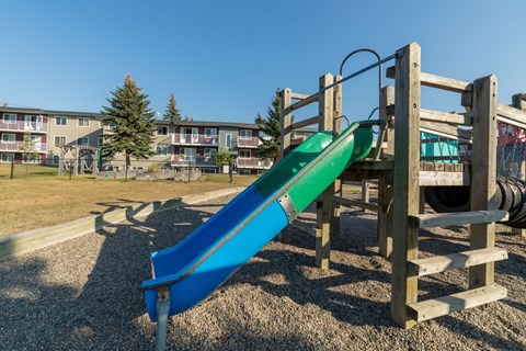 a slide in a playground with a building in the background