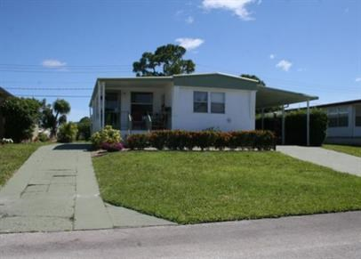 a small white house with a sidewalk in front of it