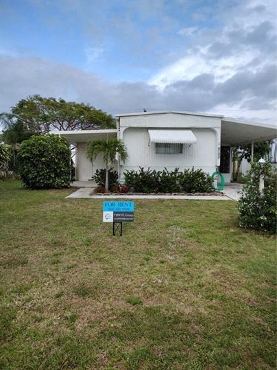 a small white house with a sign in the grass