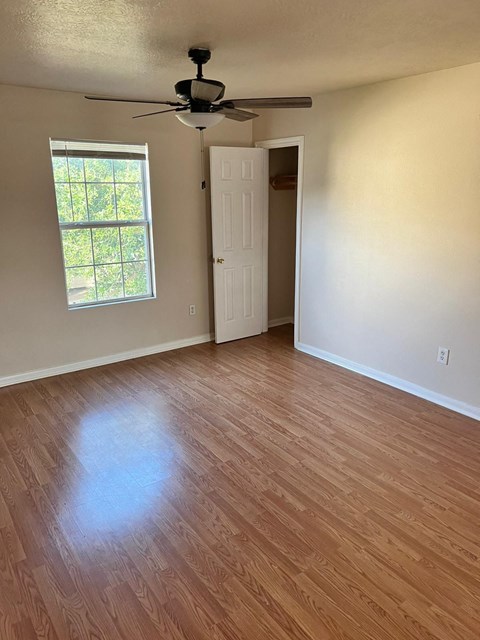 an empty living room with wood flooring and a ceiling fan