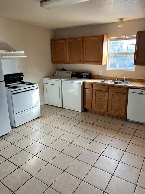 an empty kitchen with white appliances and wooden cabinets