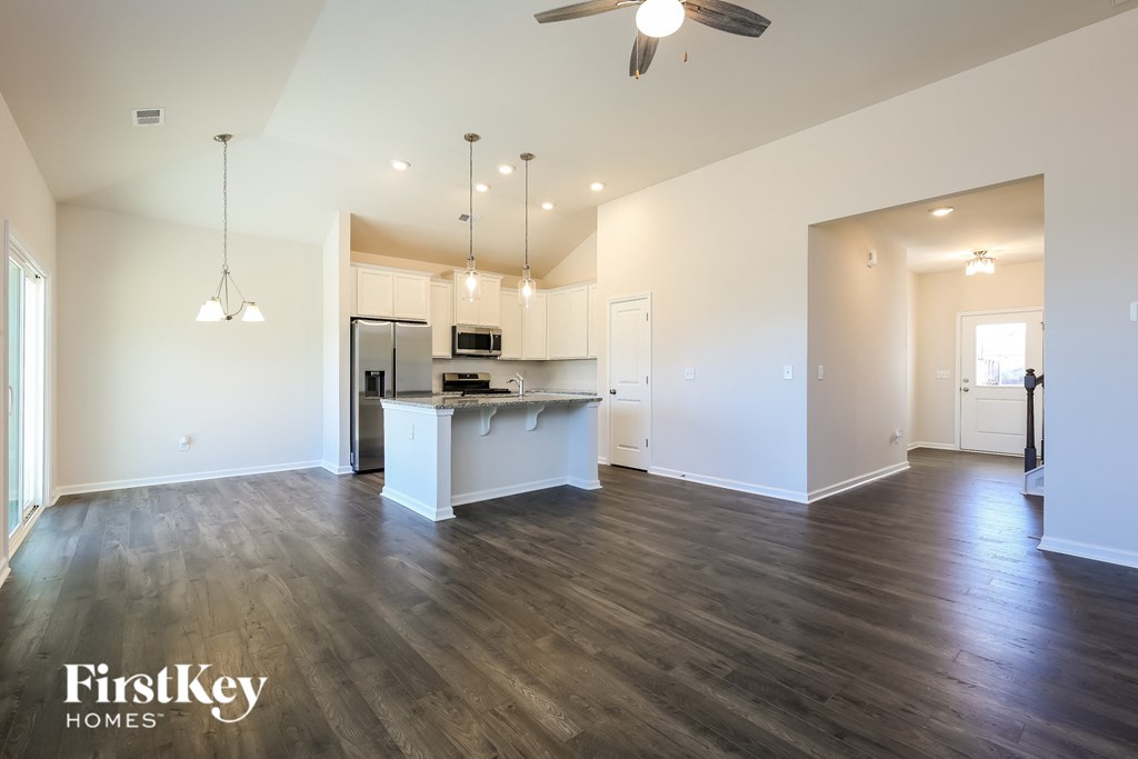A spacious kitchen and living room with wood flooring and white walls.