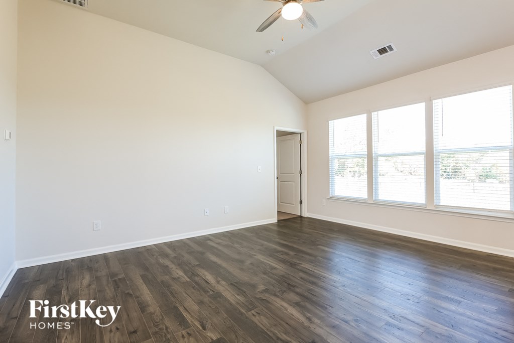 A spacious room with wooden flooring and a ceiling fan.