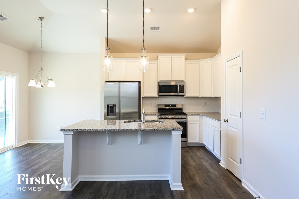 A kitchen with a granite countertop and a stainless steel refrigerator.