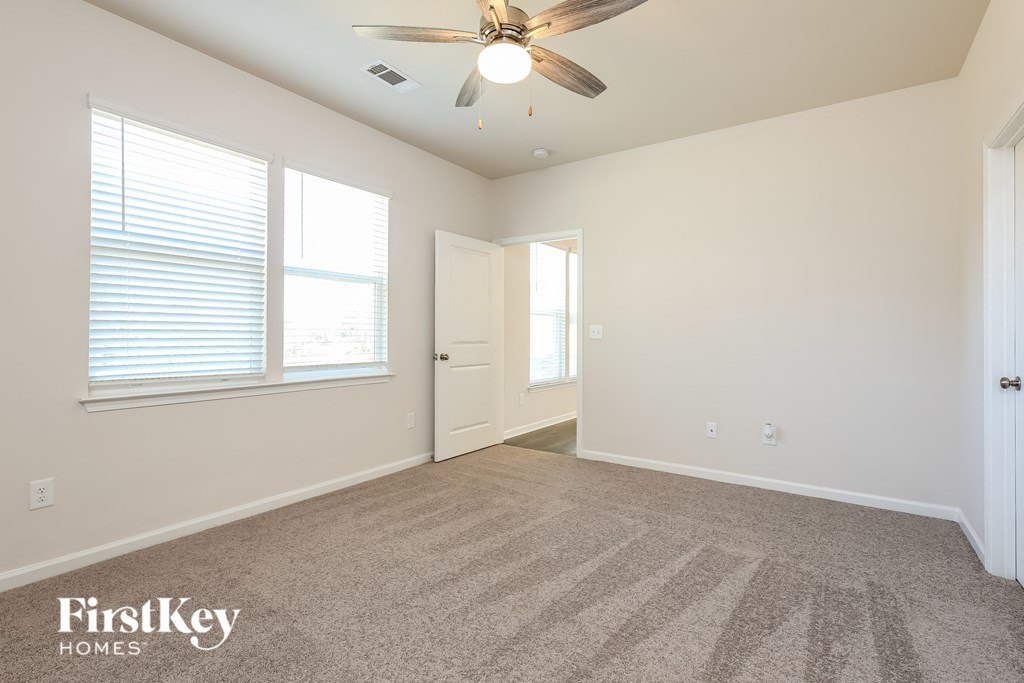A spacious room with a carpeted floor and a ceiling fan.