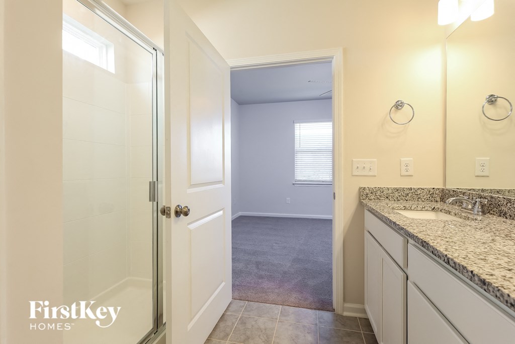 A bathroom with a sink, mirror, and a glass door.