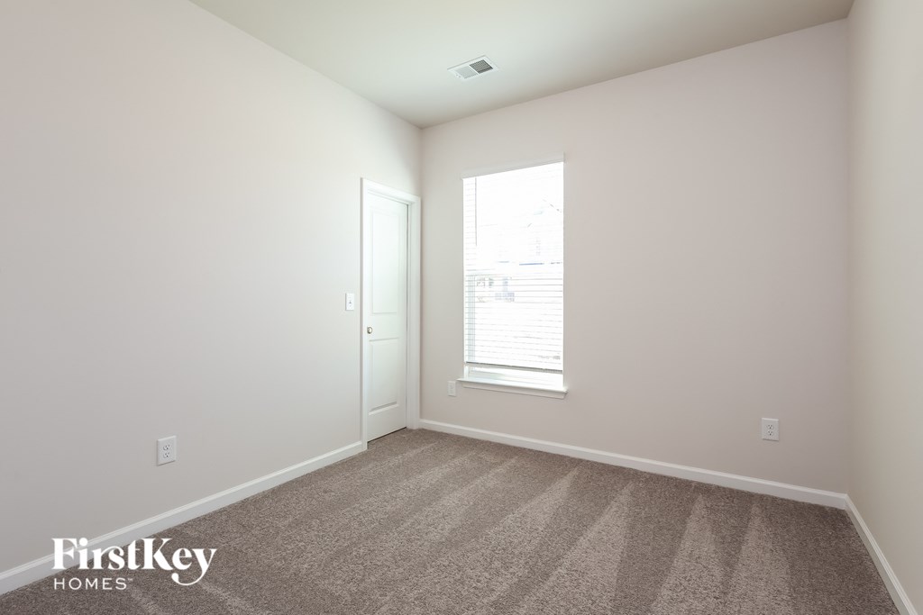 A room with a carpeted floor and a window with blinds.