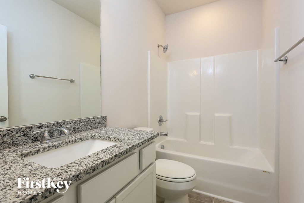 A bathroom with a marble countertop and white fixtures.