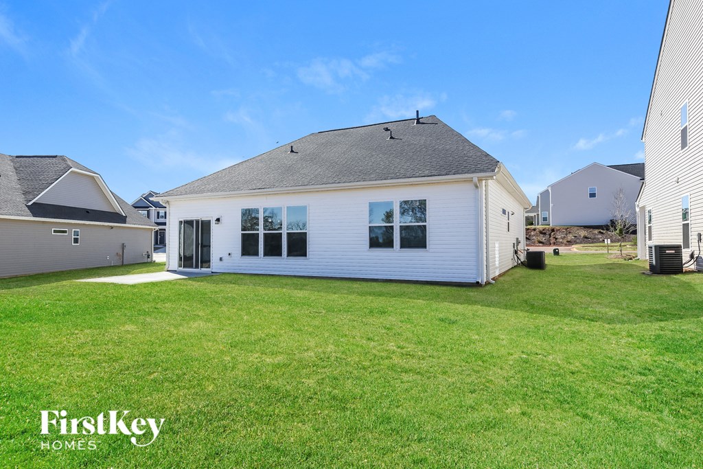 A white house with a black roof and a large lawn in front.